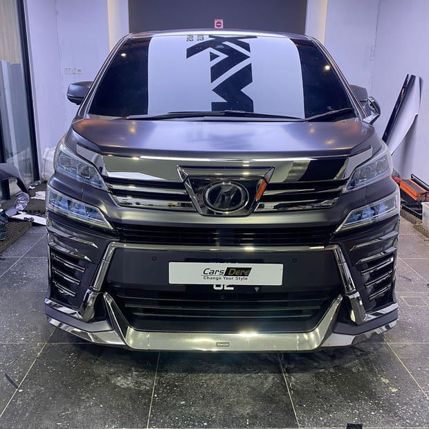 A Toyota Vellfire MPV head-on indoors in a matte metallic graphite grey film.